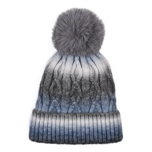 Detail of cable knit pattern and gradient blue texture on winter pom pom beanie