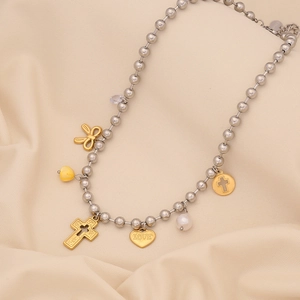 Close-up of silver beaded necklace with gold butterfly, heart, and cross charms