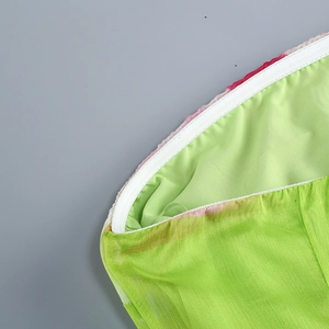 Gros plan sur la fermeture éclair blanche invisible et le tissu vert lisse de cette robe
