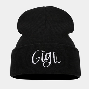 Close-up of Gigi script embroidery on a black knit beanie with premium ribbed texture