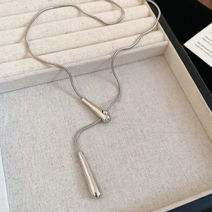 Macro shot of polished silver waterdrop pendant with snake chain on jewelry box