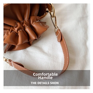 Detail of brown leather bucket bag showing white stitching and golden metal hooks