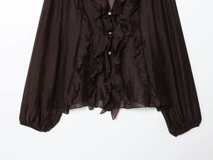 Detailed view of layered ruffles and buttons on a brown long sleeve chiffon shirt