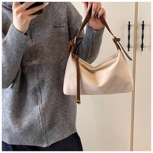 Detail of soft cream faux suede bag with dark brown strap and gold metal ball charm