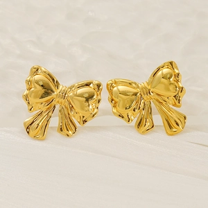 Polished gold stainless steel bow stud earrings on a textured white background