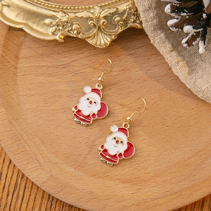 Detailed view of red and white Santa Claus hook earrings on a rustic wooden tray