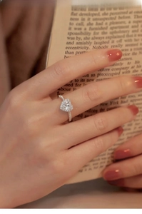 Detail of heart-shaped moissanite ring with halo setting on a model finger