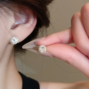 Detailed close-up of sparkling zircon stud earrings with cluster setting on the earlobe