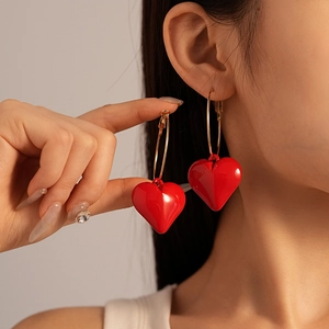 Vintage style red acrylic heart pendant earrings with gold hoops on model