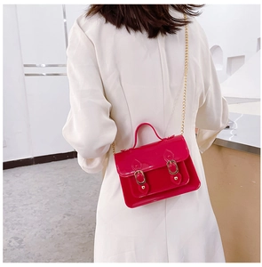 Detail view of a fuchsia jelly Cambridge bag worn as a crossbody with a gold chain.