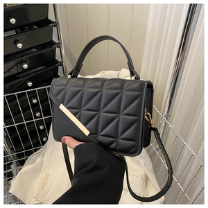 Close-up of black quilted leather handbag featuring a stylish gold bar metal clasp closure