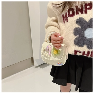 Detail of cream leather girls crossbody bag with pearl handle and knitted flower accents