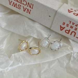 Close-up of gold and silver opal stud earrings with hammered metal texture details