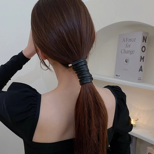 Close-up of black faux leather hair tie with gold metal clasp on a high ponytail