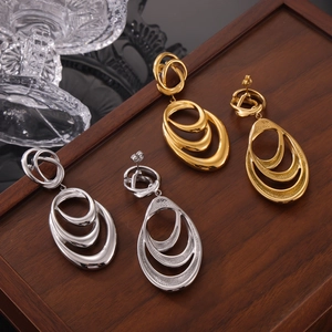Irregular geometric multilayer hoop earrings in gold and silver finish on wooden tray