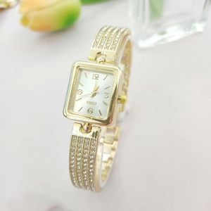 Close-up of luxury gold quartz watch with rhinestones on rectangular pearl dial