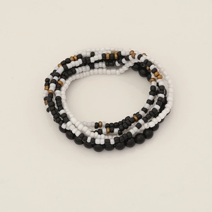 Detail shot of multi-layer Bohemian beaded bracelets in black, white, and gold seed beads
