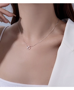 Detail shot of a silver D-letter pendant necklace with shimmering crystals on a model