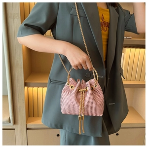 Detailed view of pink rhinestone bucket bag with golden circular handle and chain strap