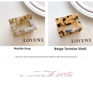 Detail view of rectangular cutout hair claws in marble grey and beige tortoiseshell acetate