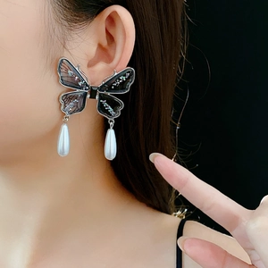 Detailed view of butterfly tassel earrings with sparkling wings and drop pearl accents