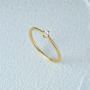 Macro shot of gold-plated silver ring with thin band and central round cubic zirconia