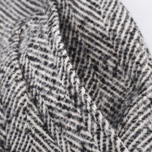 Close-up of classic black and white herringbone wool coat fabric with premium texture