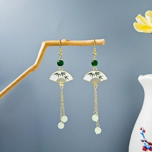 Artistic close-up of vintage bamboo tassel earrings hanging on a withered wooden branch