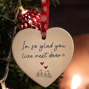 Close-up of ceramic heart ornament on a Christmas tree with a warm bokeh background