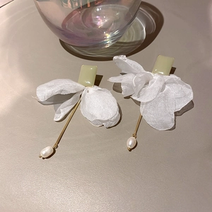 Detail of long elegant drop earrings featuring green rectangle studs and white fabric petals