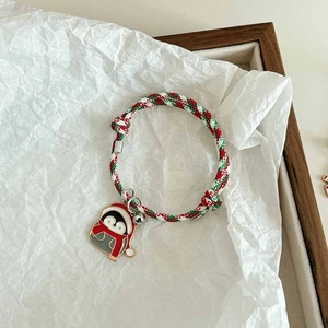 Detail of Christmas braided bracelet with cartoon penguin charm and silver bell