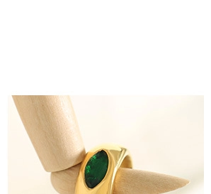 Détail d'une bague dorée vintage avec pierre verte sur un modèle de main en bois