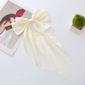 Detailed view of cream satin oversized bow hair clip with elegant long ribbons