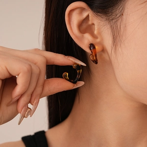 Close-up of tortoise shell resin C-shaped hoop earrings worn by a model