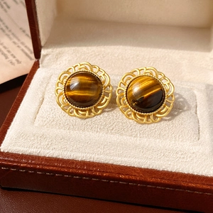 Macro shot of vintage gold earrings featuring round tiger eye stones in a jewelry box