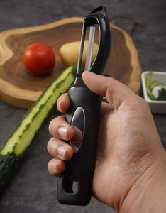 Action shot of ergonomic black peeler removing skin from a cucumber in a kitchen setting