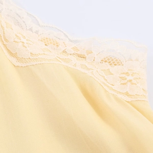 Close-up of pale yellow fabric with delicate white lace trim detailing on the top