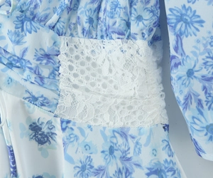 Macro detail of white floral lace stitching and blue porcelain print on a chiffon dress
