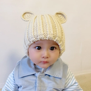 Close-up of baby beige knitted hat with bear ears and warm thick wool material