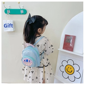 Girl's blue sequin backpack with pink shell design and pearl handle on a young model
