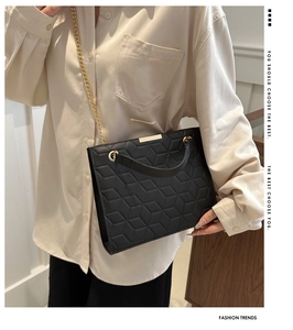 Detail of black quilted chain bag with 3D geometric pattern and metal hardware