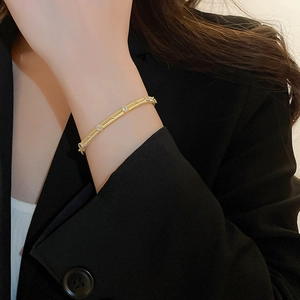 Detail of vintage gold-plated cuff bracelet with brushed texture and zircon stones