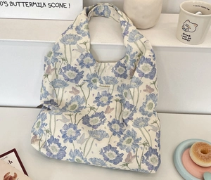 Detailed view of floral canvas tote bag with butterfly patterns and brand woven label