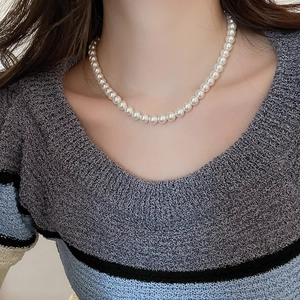 Close-up of a French style pearl necklace worn with a blue striped knit sweater