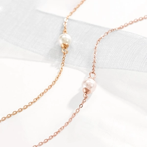 Detailansicht der minimalistischen roségoldenen Kette mit glänzenden weißen Perlen und Band