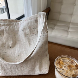 Dettaglio ravvicinato della borsa tote in tela crema con puntini di fibre colorate