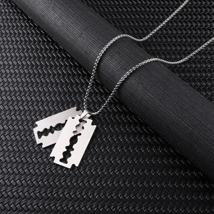 Macro shot of silver stainless steel razor blade pendant and chain on black background