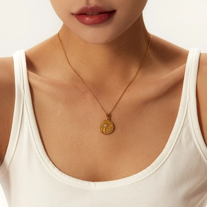 Detailed shot of golden coin necklace with sun moon relief and a zircon stone