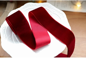 Close-up of luxury burgundy velvet ribbon with white edges on a white porcelain plate
