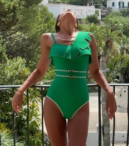 Detail of green one-piece swimsuit featuring scalloped edges and gold belt buckle